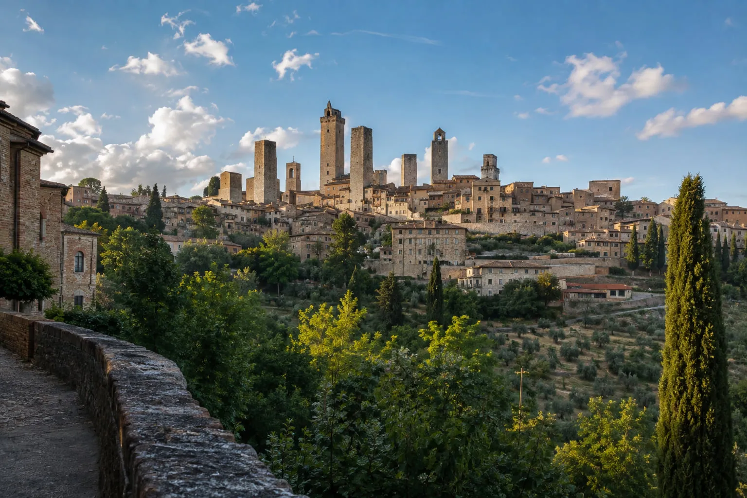 The medieval towers of San Gimignano rising above terracotta rooftops and olive groves under a clear sky
